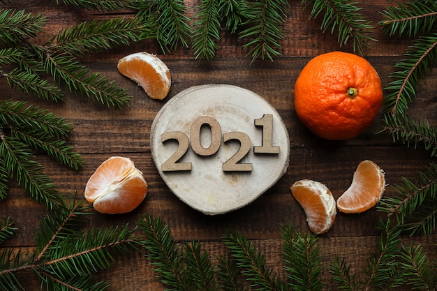 Piatto di Capodanno laici con numeri in legno 2021, Natale e mandarino su fondo in legno.
