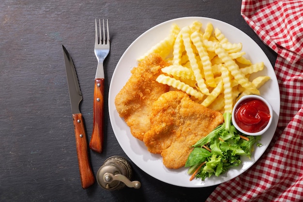 Piatto di carne di pollo impanata fritta o Schnitzel con patatine fritte e insalata