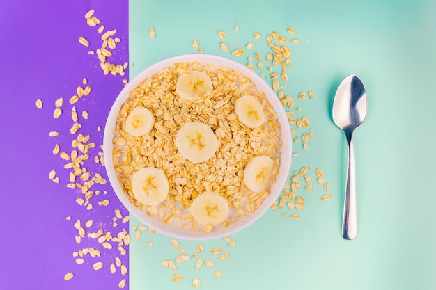 Piatto di farina d'avena naturale con banane e un bicchiere di latte fresco con uno sfondo color pastello