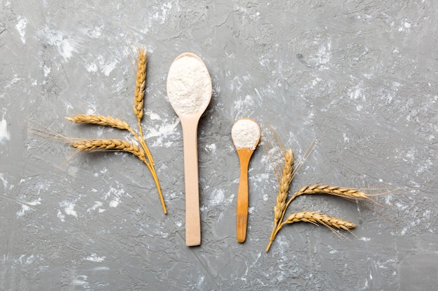 Piatto di farina di grano in ciotola di legno con spighette di grano su sfondo colorato Crisi mondiale del grano