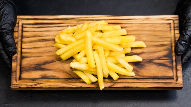 Piatto di fast food. Vista dall'alto di patatine fritte salate su tavola di legno rustica nelle mani dello chef.