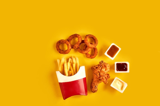 Piatto di fast food vista dall'alto Patatine fritte hamburger maionese e salse di ketchup su sfondo giallo