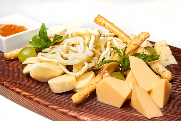 Piatto di formaggi con feta parmigiano e bastoncini di mozzarella treccia di formaggio con miele