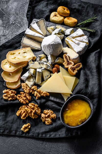 Piatto di formaggi con formaggi biologici, fichi, noci su sfondo nero. Vista dall'alto. Gustoso antipasto di formaggio