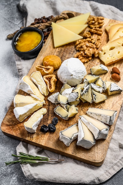 Piatto di formaggi con formaggi biologici francesi, fichi, noci su sfondo grigio. Vista dall'alto. Gustoso antipasto di formaggio