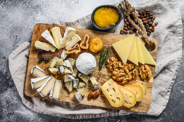 Piatto di formaggi con formaggi biologici francesi, fichi, noci su sfondo grigio. Vista dall'alto. Gustoso antipasto di formaggio