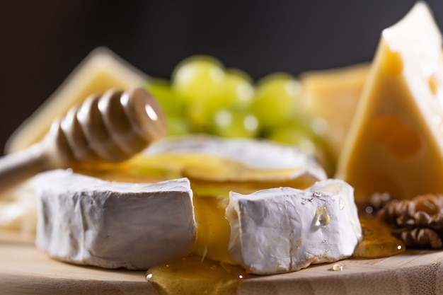 Piatto di formaggi, miele che versa sul formaggio camembert