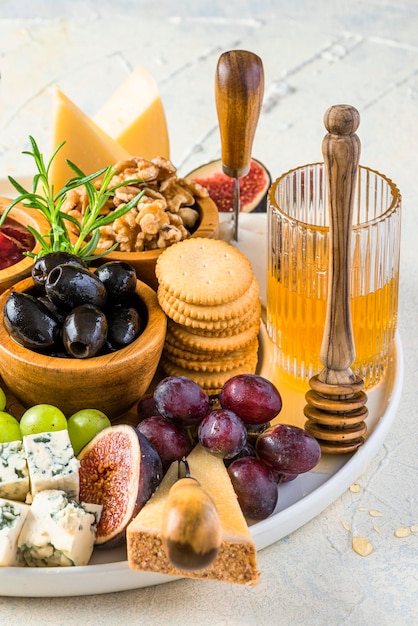 Piatto di formaggi o tagliere di formaggi con frutta, erbe aromatiche, miele e cracker