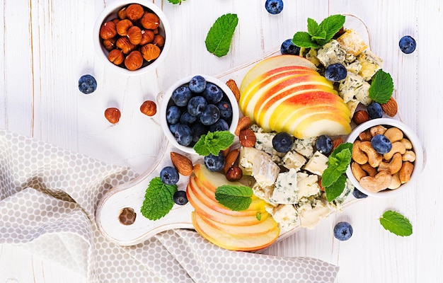 Piatto di formaggio con formaggi assortiti mirtilli mele noci su tavola bianca piatto di formaggi italiano e frutta vista dall'alto