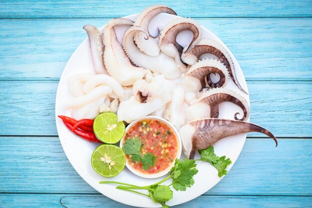 Piatto di frutti di mare calamari su piatto bianco Calamari freschi cotti a vapore con insalata di verdure limone lime e salsa di frutti di mare salsa chili servire sul tavolo tentacoli di polpo seppie gourmet dell'oceano