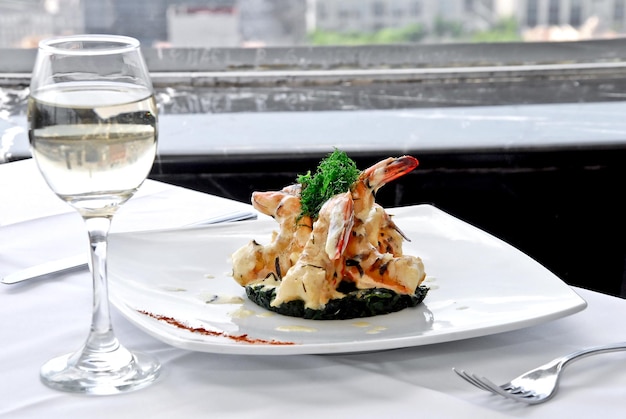 piatto di gamberi arrostiti al burro bicchiere di vino bianco, tavolo da ristorante, vista panoramica sulla città, cibo
