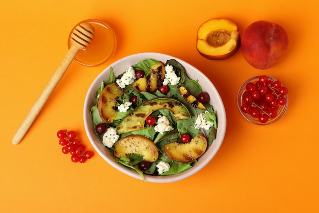 Piatto di insalata con pesca grigliata su fondo arancia