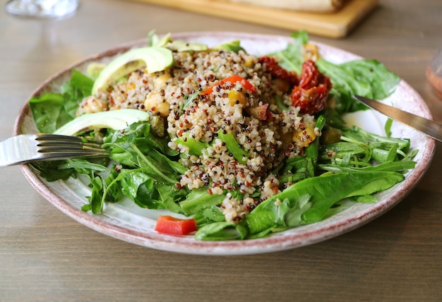 Piatto di insalata di quinoa con rucola e avocado servito su tavola di legno