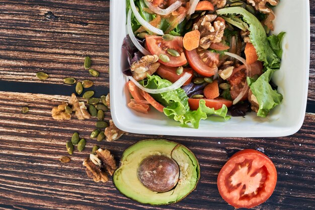 Piatto di insalata di verdure su fondo di legno dell'annata. Cibo vegetariano sano, vista dall'alto.