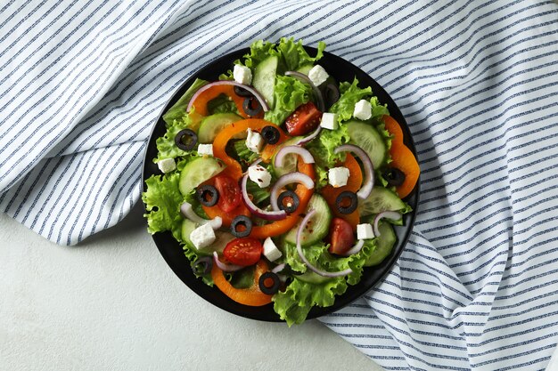 Piatto di insalata greca e asciugatutto su bianco testurizzato