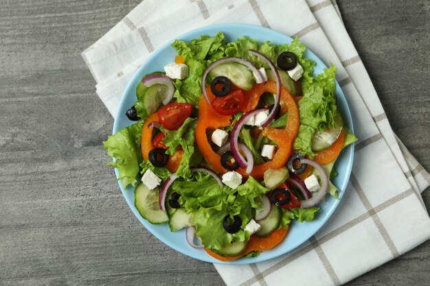 Piatto di insalata greca e asciugatutto su grigio testurizzato