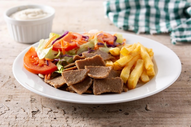 Piatto di kebab, verdure e patatine fritte sul tavolo di legno