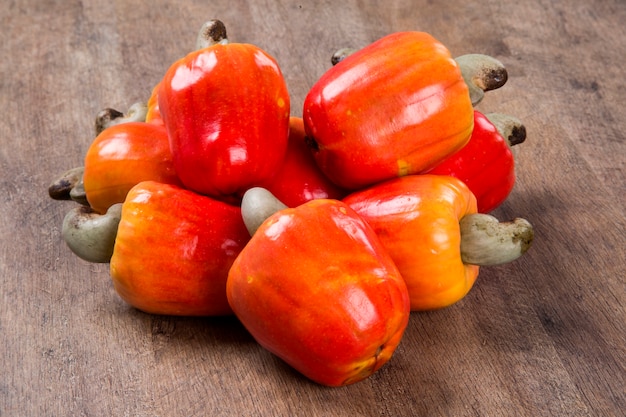 piatto di legno con alcuni anacardi su una superficie di legno. Frutta fresca.