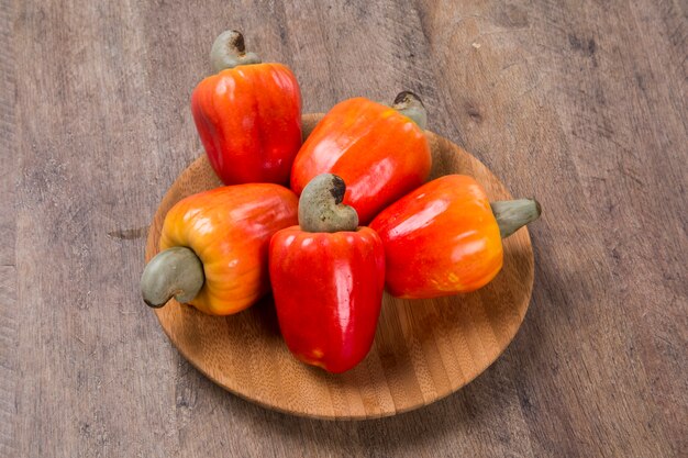 piatto di legno con alcuni anacardi su una superficie di legno. Frutta fresca.