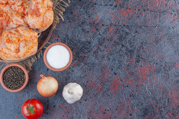 Piatto di legno di pollo intero marinato sulla superficie di marmo