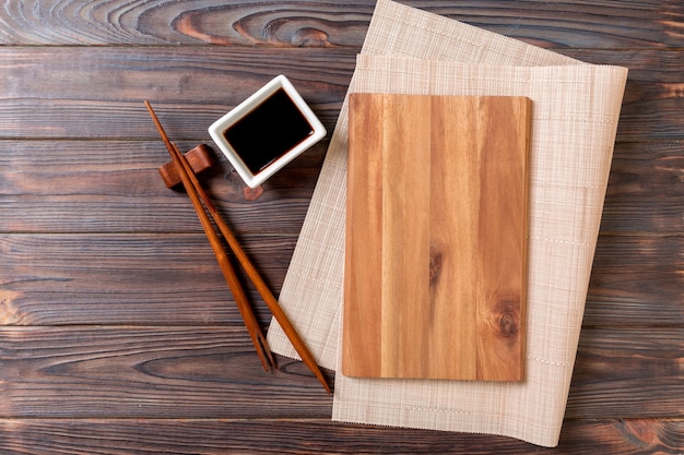 Piatto di legno rettangolare vuoto per sushi con salsa e bacchette sulla tavola di legno