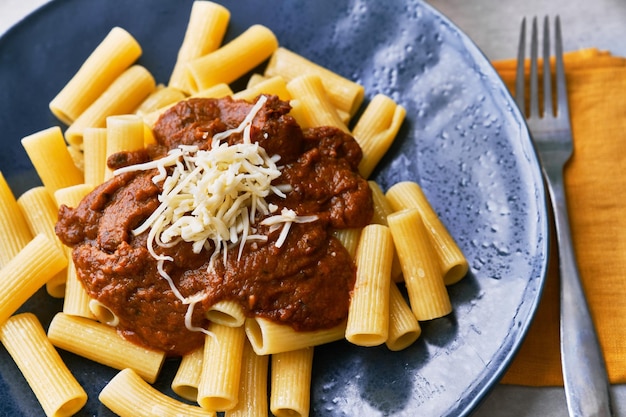 Piatto di maccheroni pasta italiana con salsa di pomodoro e formaggio su una superficie di cemento