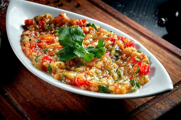 Piatto di melanzane arabo tradizionale Baba Ghanoush con olio d'oliva ed erbe sulla tavola di legno