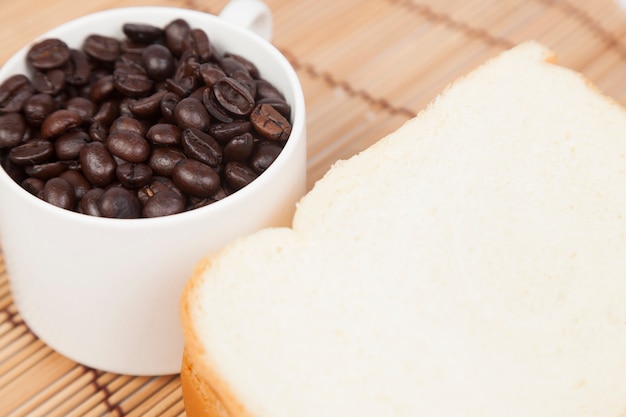 Piatto di pane e tazza con chicchi di caffè.