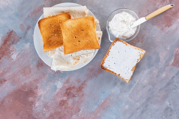 Piatto di pane tostato fritto con panna acida sul tavolo di marmo.