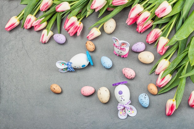 Piatto di Pasqua con graziose uova di conigli e tulipani Arredamento tradizionale biglietto d'auguri festivo concetto di vacanza pietra grigia sfondo cemento vista dall'alto