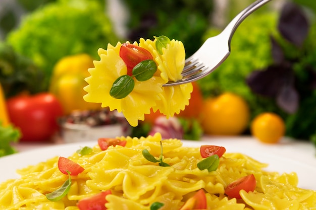 Piatto di pasta rigata italiana cotta con pomodori e foglie di basilico con molto cibo intorno food