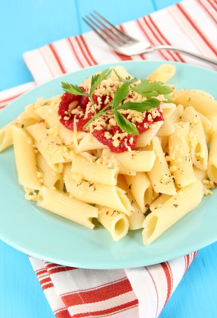 Piatto di pasta rigatoni con salsa di pomodoro su tavola di legno blu da vicino