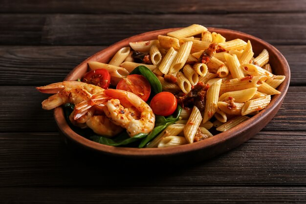 Piatto di pasta saporita con gamberetti e pomodori su fondo di legno