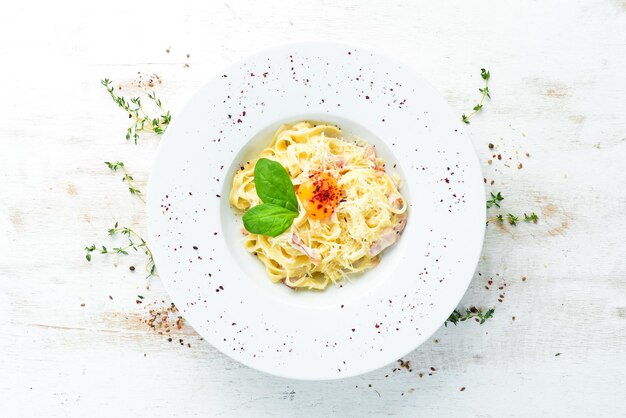 Piatto di pasta tradizionale italiano spaghetti alla carbonara con tuorlo di parmigiano su un piatto Vista dall'alto Spazio libero per la copia