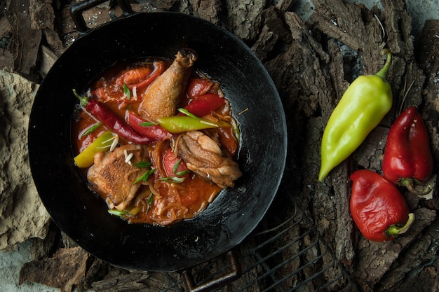 Piatto di pollo con verdure in padella sullo sfondo di corteccia d'albero