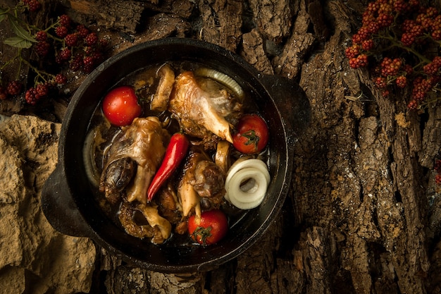 Piatto di pollo con verdure in padella sullo sfondo di corteccia d'albero