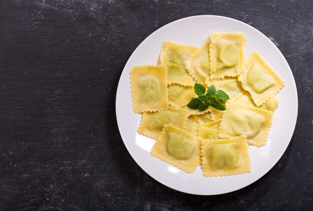 Piatto di ravioli con basilico su scuro, vista dall'alto