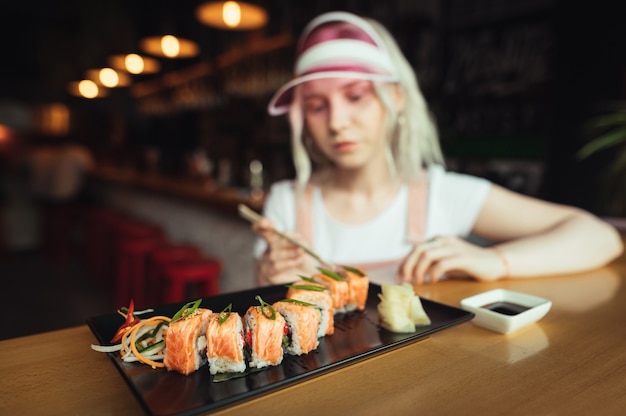 Piatto di rotoli di sushi nel ristorante con la donna che tiene le bacchette