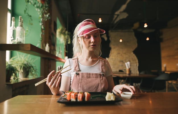 Piatto di rotoli di sushi nel ristorante con la donna che tiene le bacchette