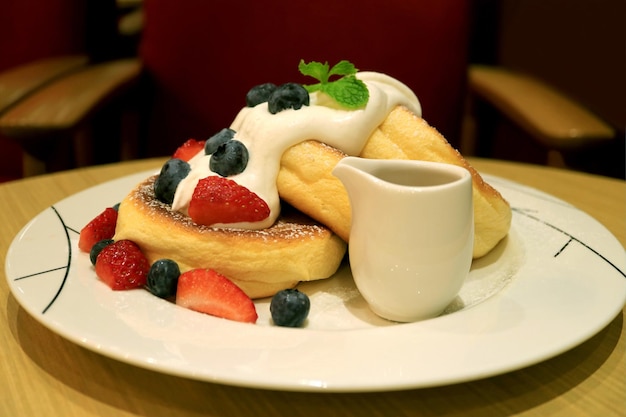 Piatto di soffici frittelle di soufflé guarnite con frutti di bosco freschi e crema al mascarpone