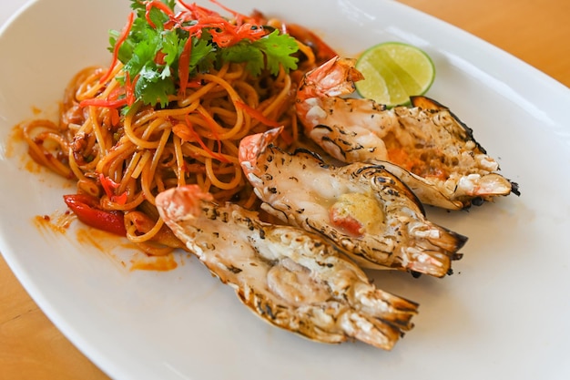 Piatto di spaghetti con spaghetti saltati in padella con verdure alle erbe speziate gustose appetitose tagliatelle asiatiche mescolano frutti di mare saltati in padella gamberetti su piatto bianco