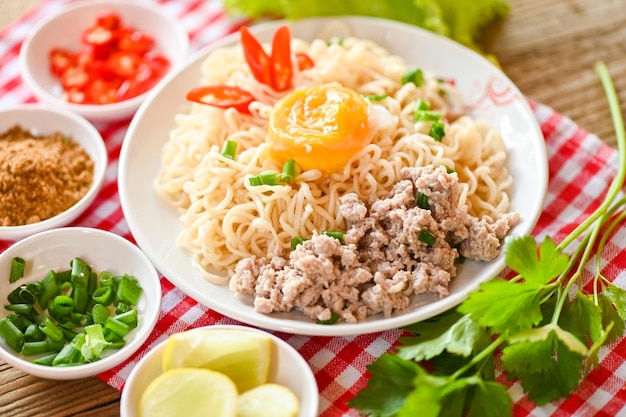 Piatto di tagliatelle con uovo tritato di maiale verdura cipollotto limone lime lattuga sedano e peperoncino sul tavolo cibo spaghetti istantanei cucina gustoso mangiare con ciotola zuppa di noodle