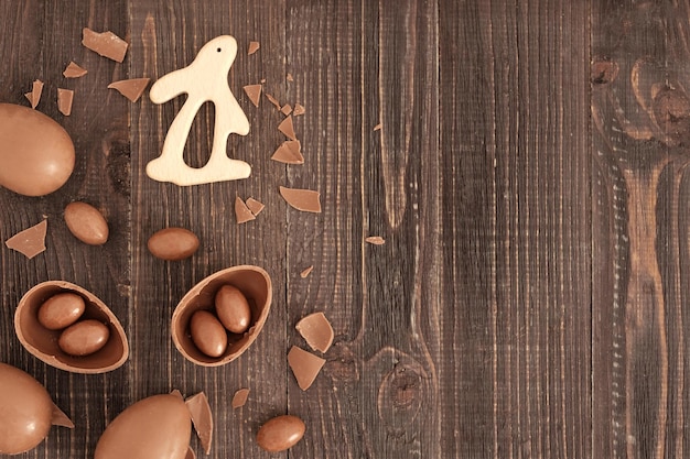 Piatto di uova di cioccolato caramelle e coniglietto sullo sfondo di legno Decorazione pasquale fatta a mano