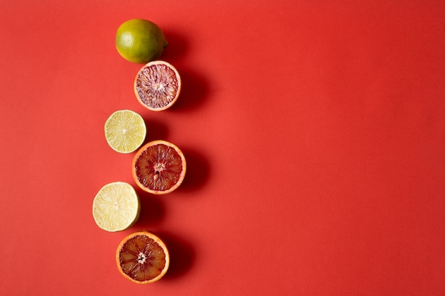 Piatto distesi il limone fresco crudo e agrumi arancione su sfondo rosso.