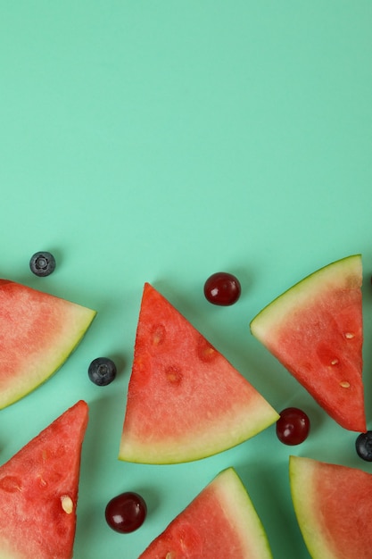 Piatto disteso con fette di cocomero e frutti di bosco su sfondo di menta