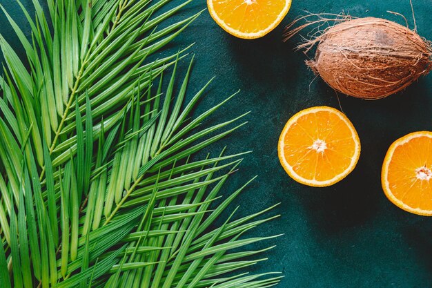 Piatto estivo con arance a foglia di palma e cocco su sfondo verde scuro