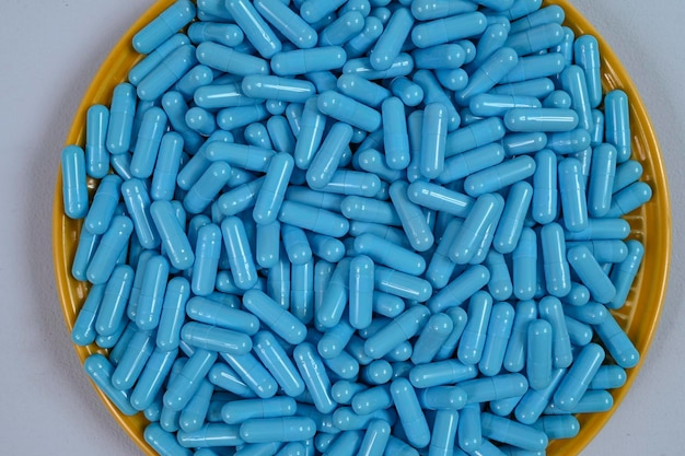 Piatto giallo pieno di capsule di medicina blu che rappresentano l'overdose di droga