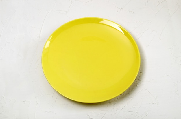 Piatto giallo vuoto su priorità bassa strutturata bianca.