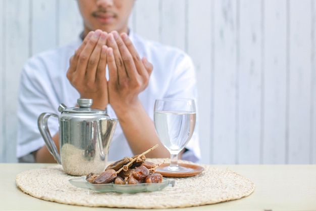 Piatto Iftar con mano di uomo musulmano che prega ad Allah