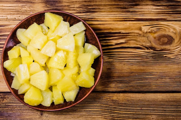 Piatto in ceramica con ananas in scatola tritato su tavola in legno rustico. Vista dall'alto